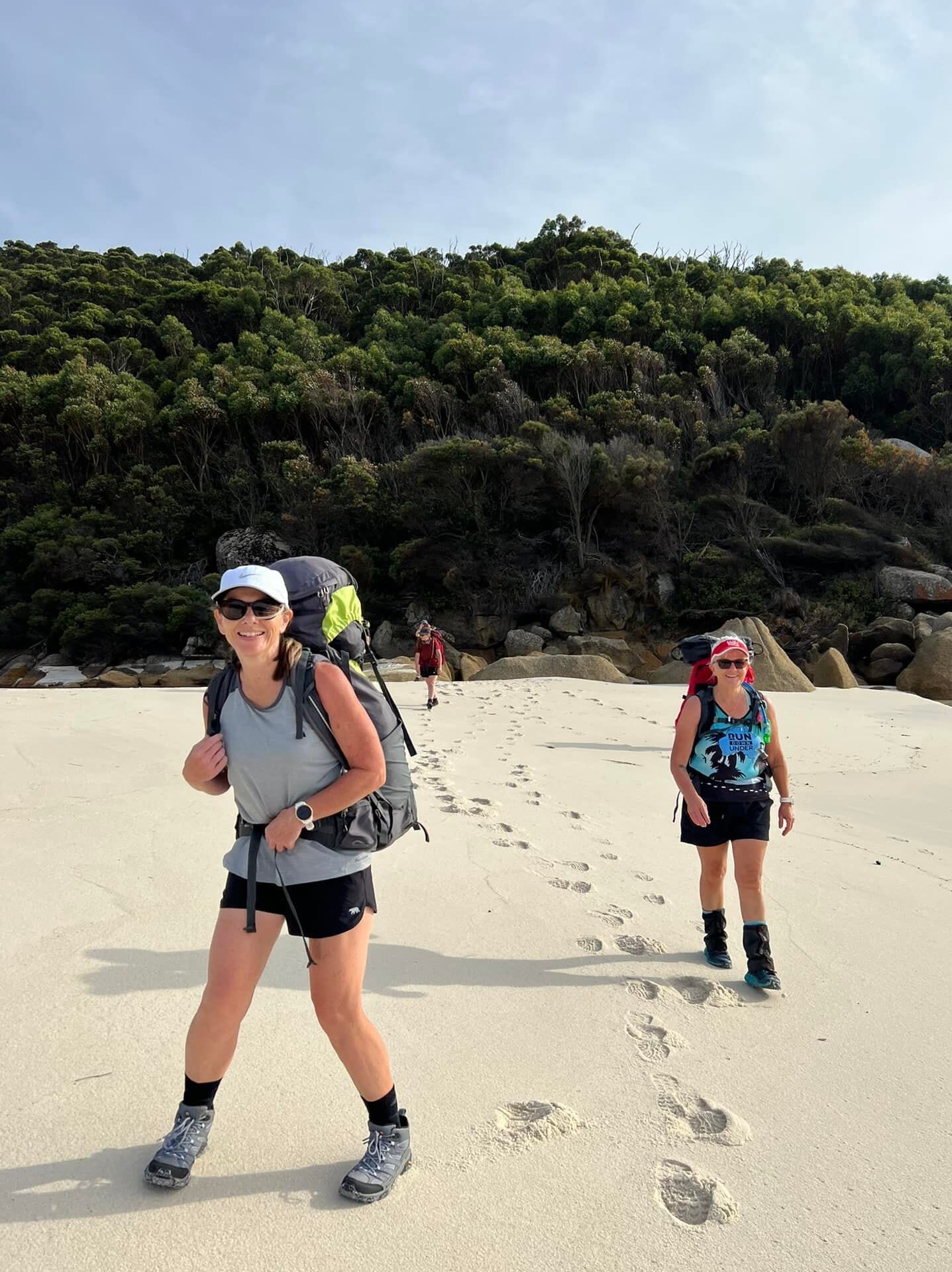 Hikers on a sandy beach trail.