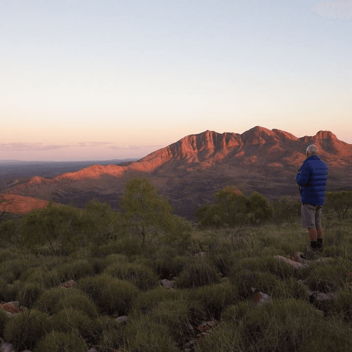 Man overlooking mountainous landscape at sunset