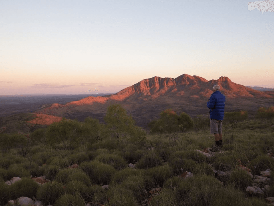Man overlooking mountainous landscape at sunset